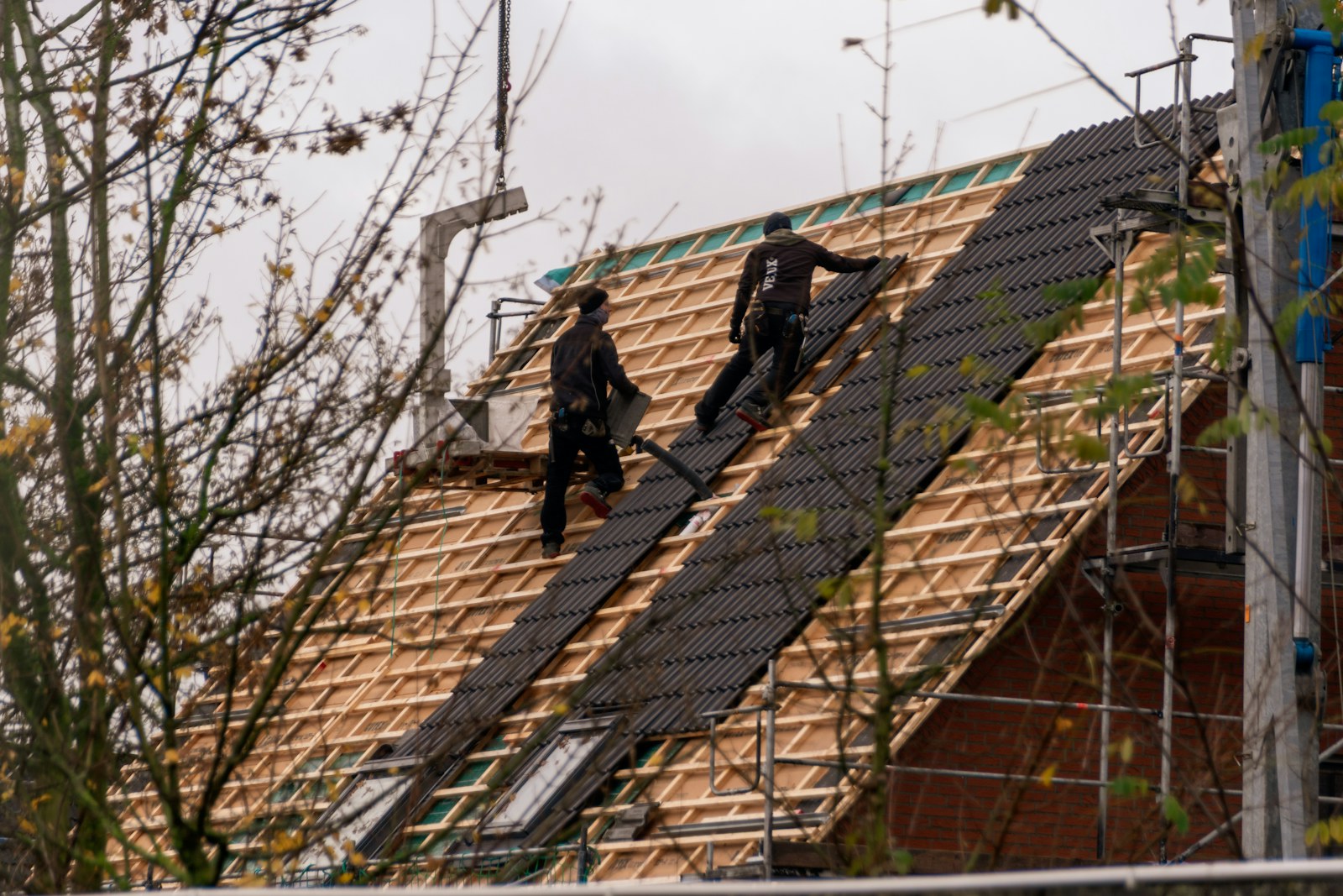 Installers laying shingles on a residential roof